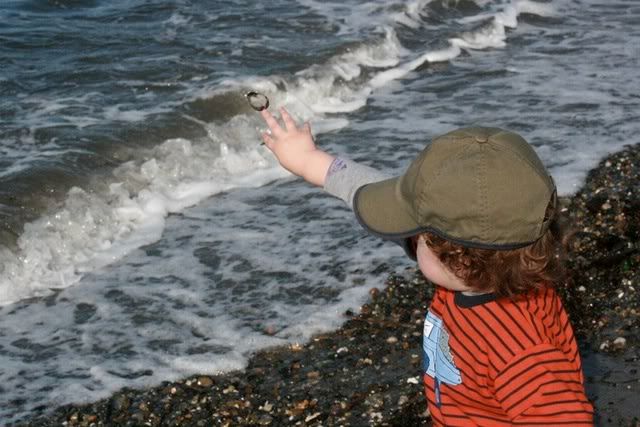 toddler throwing rocks into ocean