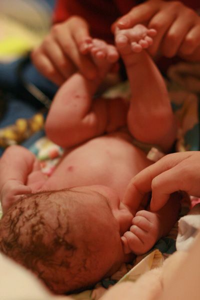home birth midwife — midwives examining newborn baby at homebirth