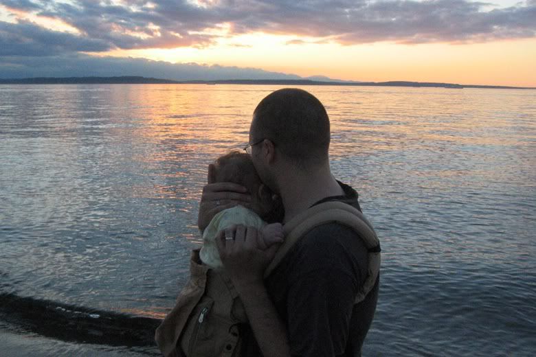 daddy with newborn in Ergo baby carrier walking along beach