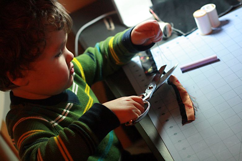 Photo Credit: Hobo Mama boy cutting with scissors to help sew — black mei tai tutorial