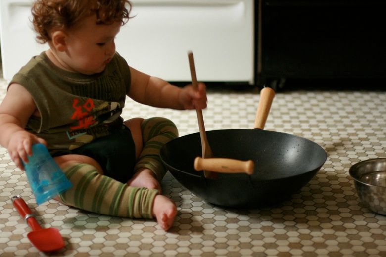baby stirring flour and water in a wok — toddler cooking in the kitchen
