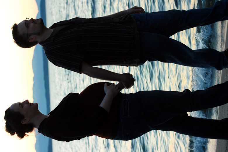 birth — walking along the beach hand in hand with partner — pregnancy pics belly bump 34 weeks