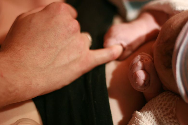 birth — newborn holding dad's finger
