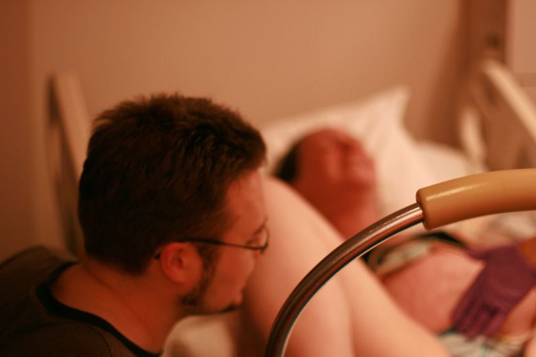 birth — partner watching the pushing during labor at hospital