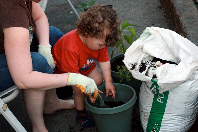 boy helping mom scoop the soil for container garden
