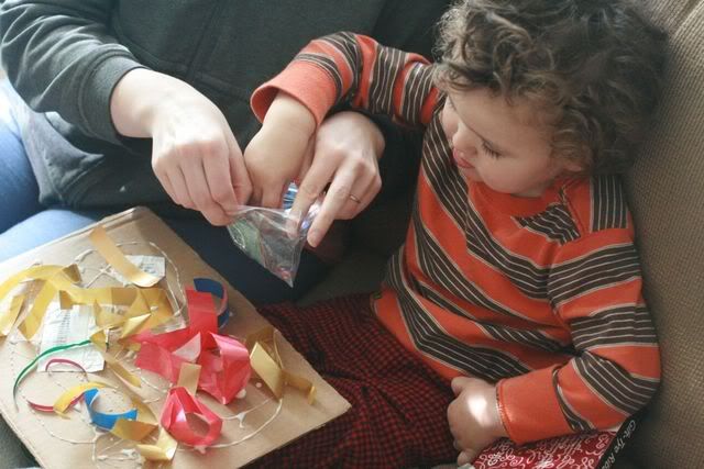 toddler sprinkling glitter on the collage